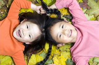 two girls laying on the ground in leaves