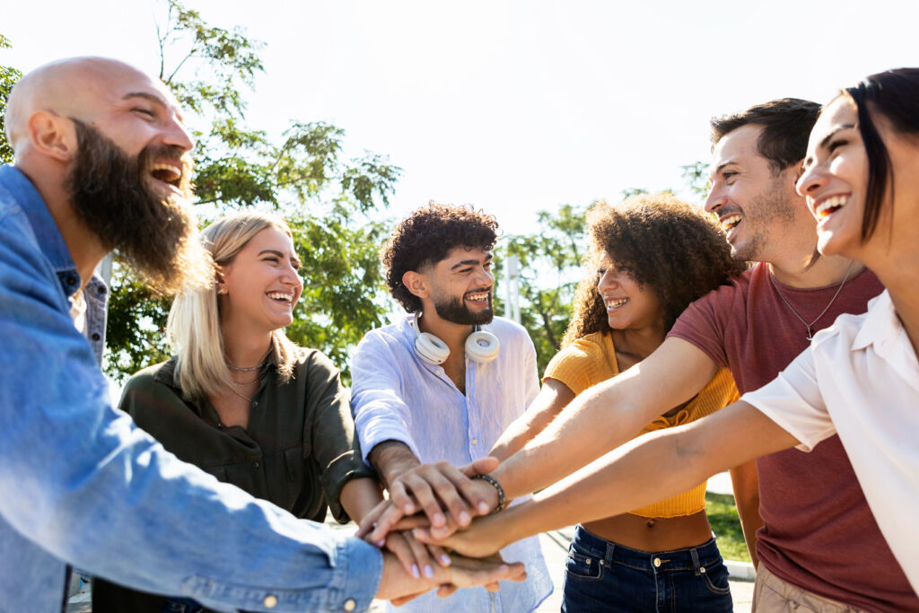 Group of united multiracial people stacking hands together - Cooperation, collaboration, community and unity concept with multiethnic young people